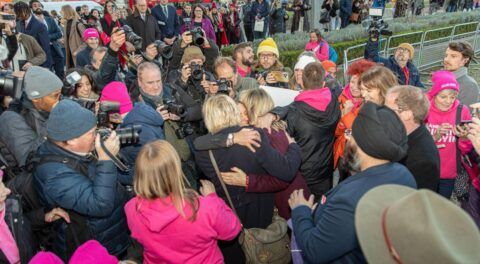 Kim Leadbeater MP hugging two campaigners, surrounded by other campaigners and the media.